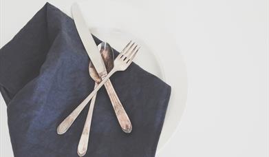 Knife, folk and spoon on blue napkin and white plate