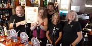 East Anglia CAMRA Regional Director Presenting a certificate stating East Anglia CAMRA Regional Pub Of The Year to the Landlord (Pharez Smith) togethe